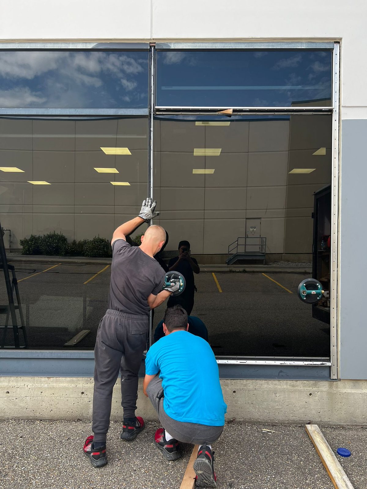 Technicians handling a commercial glass panel