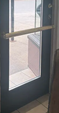Detail of the door’s horizontal brass hardware in the customer photograph.