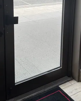 Detail of the lower entrance door glass and frame in the customer photograph.